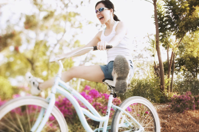 Woman on Bicycle with Legs Outstretched --- Image by © Royalty-Free/Corbis