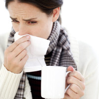 Woman Holding a Mug with a Handkerchief to Her Nose --- Image by © Royalty-Free/Corbis